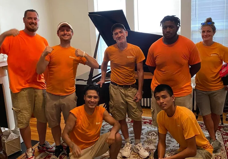 Smart Move crew gathered beside a grand piano indoors