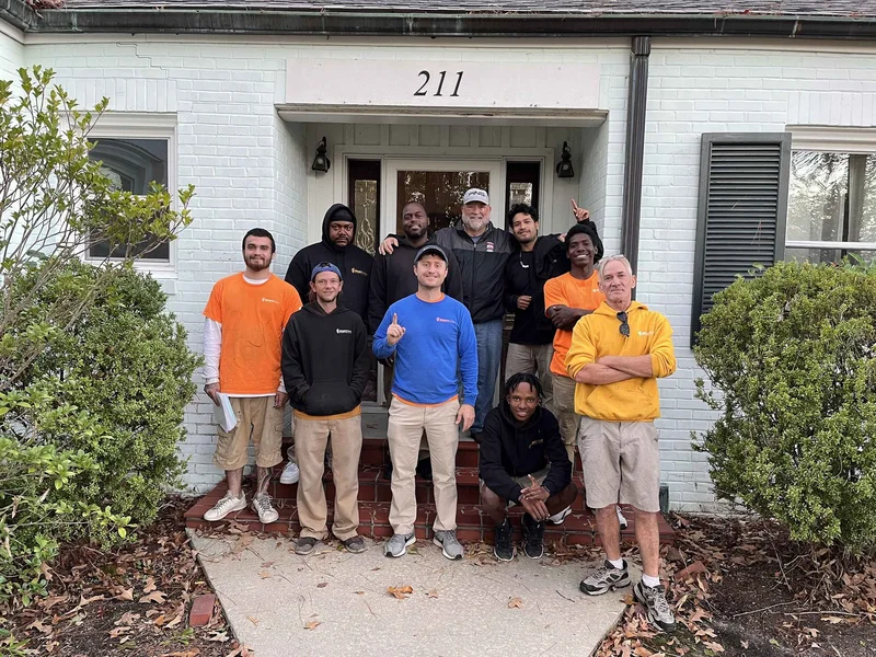 Moving crew and a group gathered outside a white house