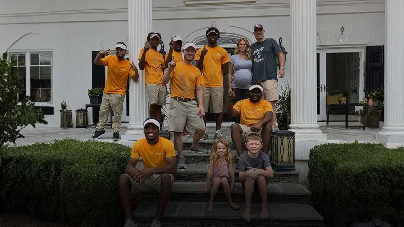 Moving crew and a family gathered on the front steps of a home