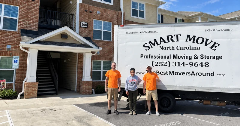 Two moving crew members and a customer beside a truck outside apartments